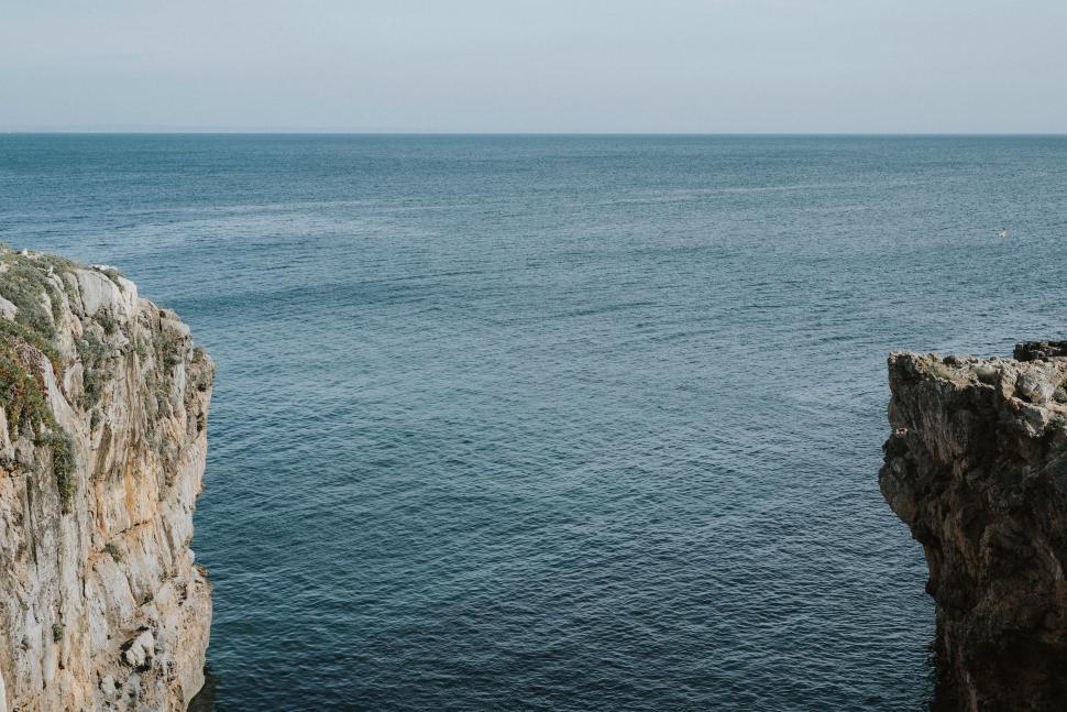 Free Image of Man Standing on Cliff Next to Ocean 