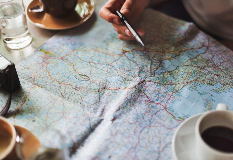 Free Image of Person Sitting at Table With Map and Cell Phone 
