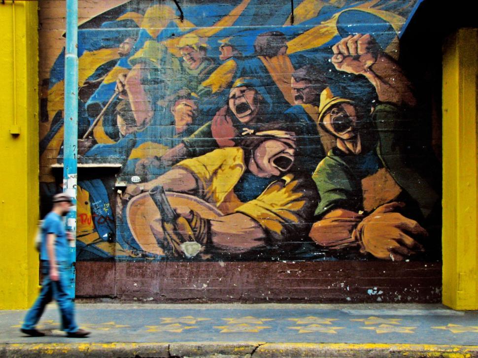 Free Image of Man Walking Past Wall With Painting 