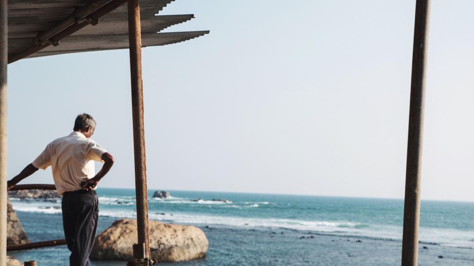 Free Image of Man Standing on Porch Next to Ocean 
