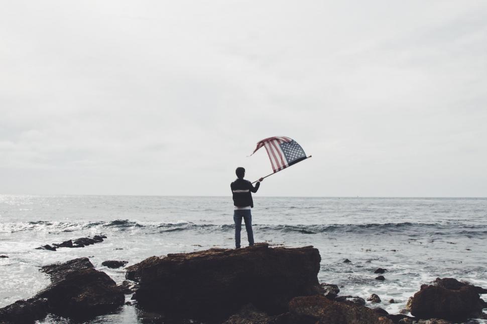 Free Image of Man Standing on Rock Holding Kite 