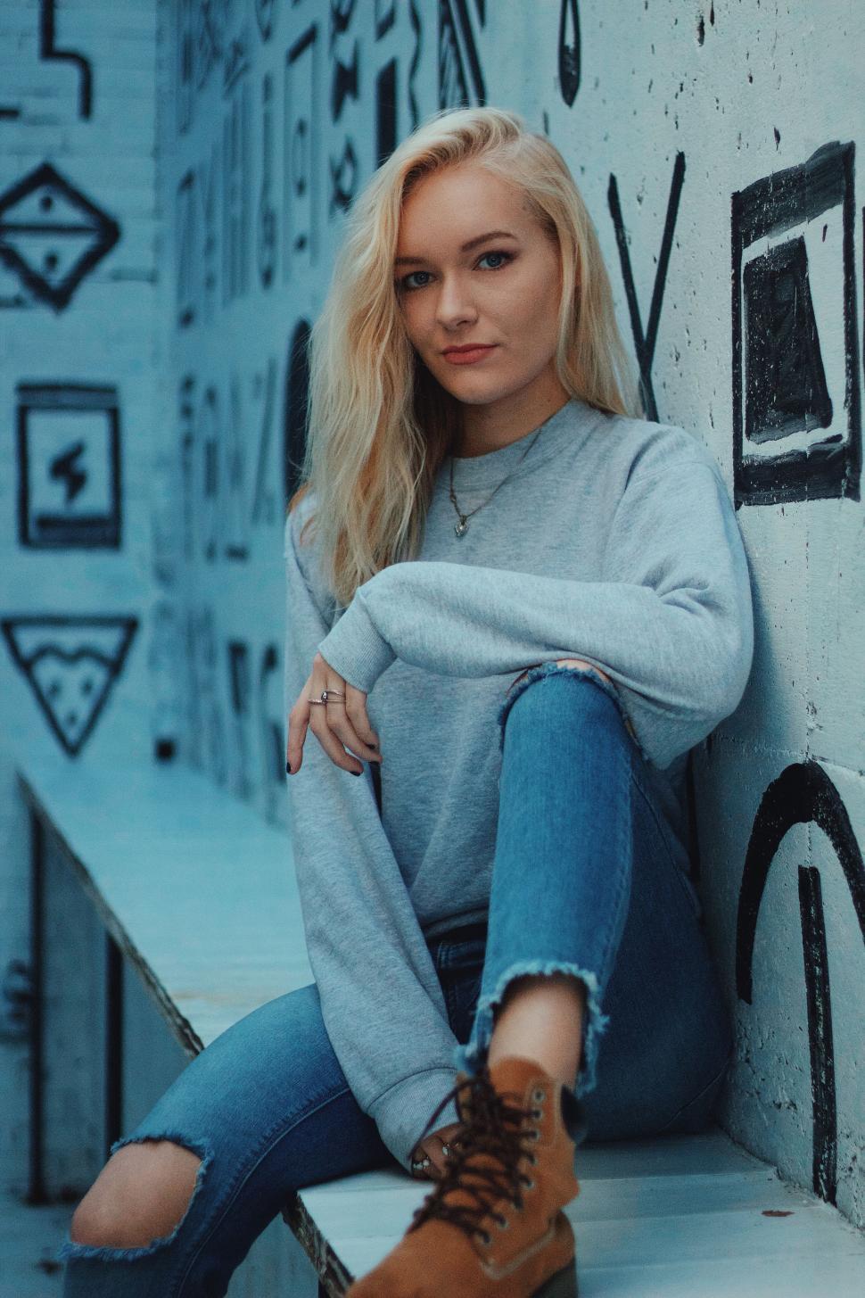 Free Image of Woman Sitting on a Wall With Crossed Legs 
