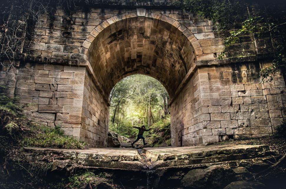 Free Image of Man Sitting on Old Stone Bridge 