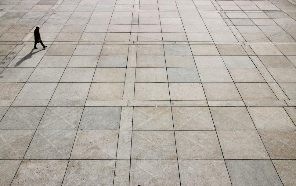 Free Image of Person Walking Down Sidewalk With Kite in Air 