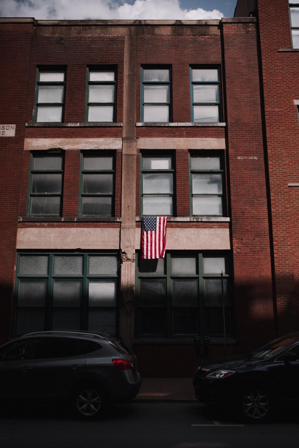 Free Image of Two Cars Parked in Front of a Tall Building 