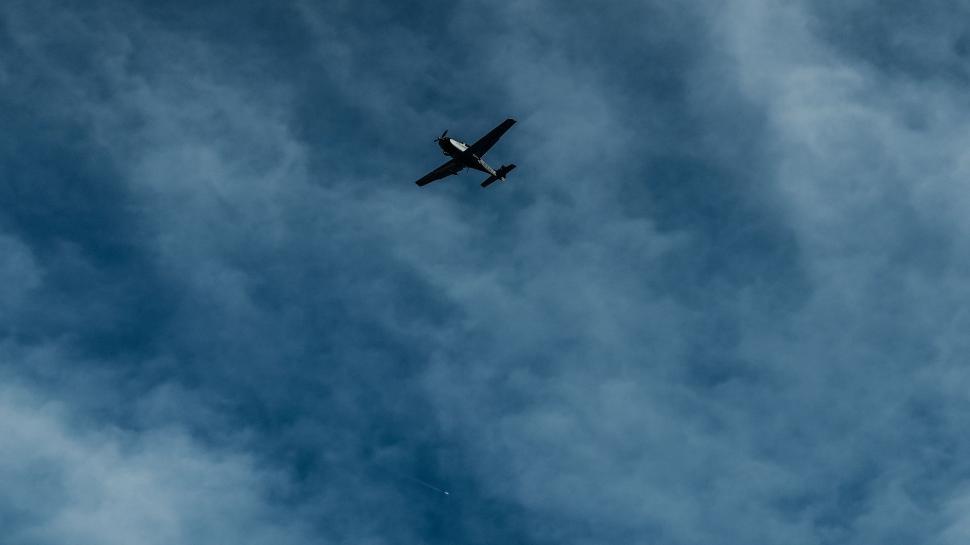 Free Image of A Plane Flying Through a Cloudy Blue Sky 
