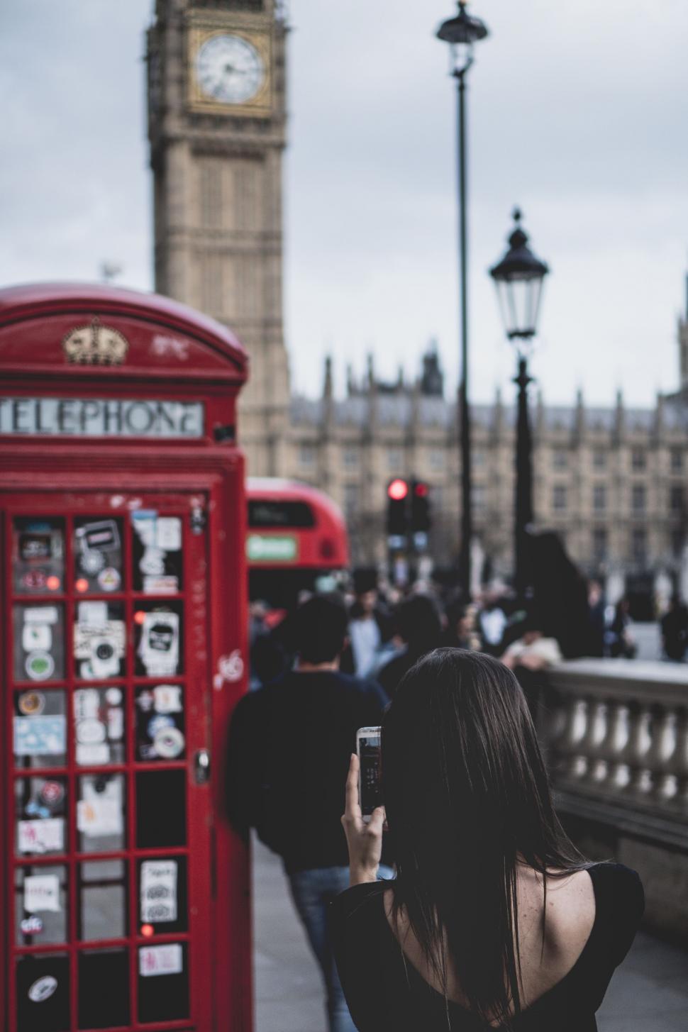 Free Image of Woman Taking Picture of Red Phone Booth 