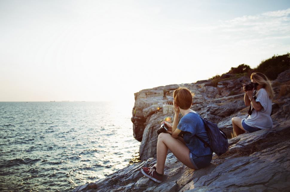 Free Image of Couple Sitting on Rock by Ocean 