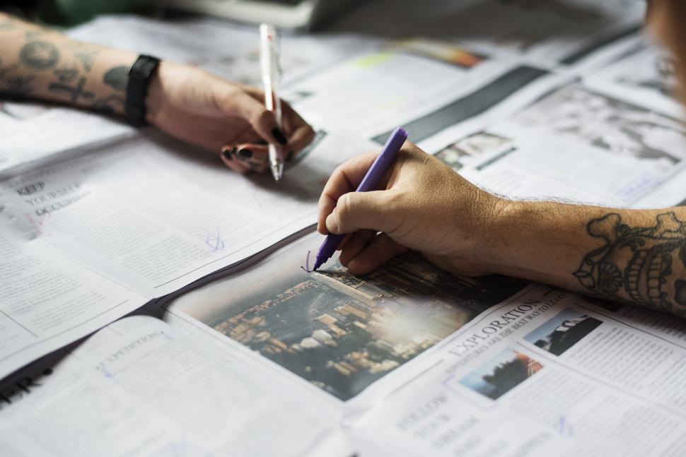 Free Image of Man With Tattoo Writing on a Piece of Paper 