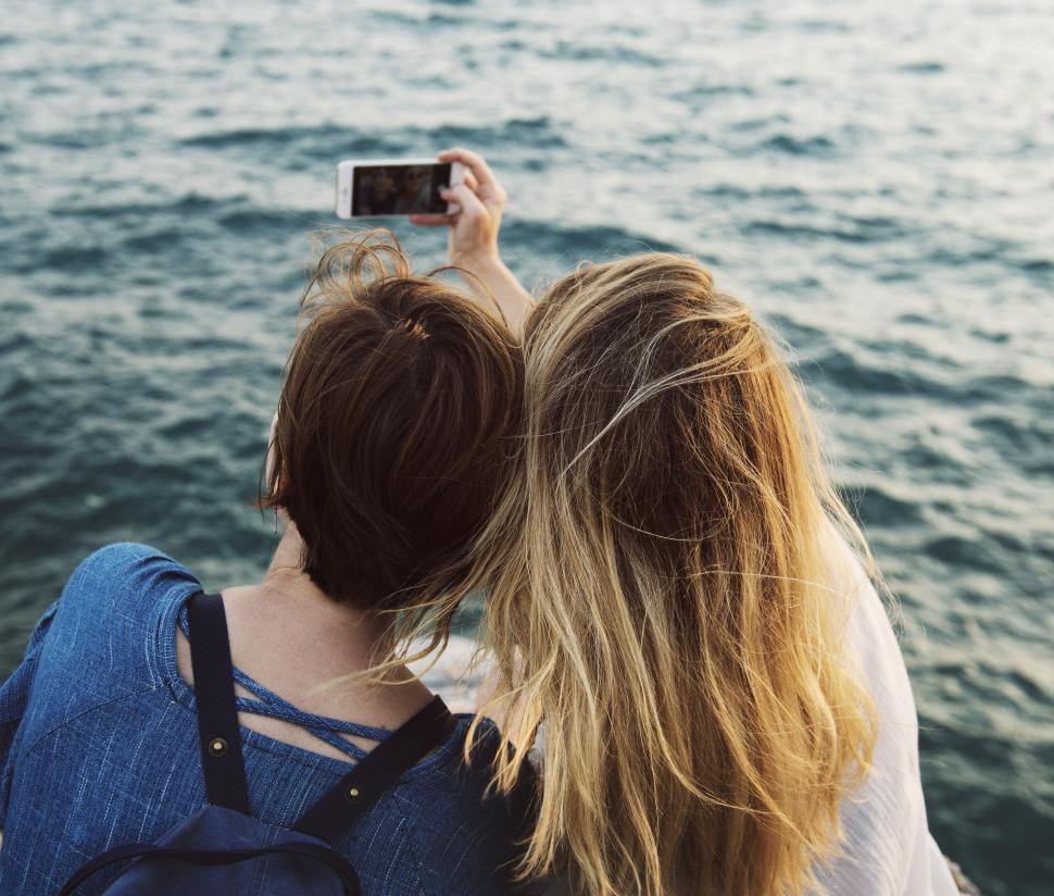 Free Image of Two People Taking a Picture of a Body of Water 