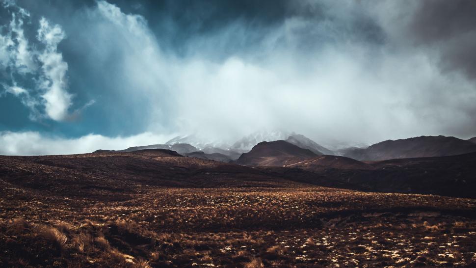 Free Image of Cloudy Sky Over Mountain Range With Distant Rainbow 