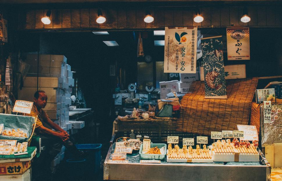 Free Image of Man Sitting in Front of Food Store 