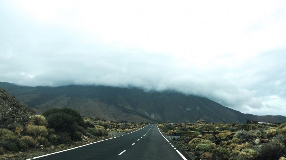 Free Image of Car Driving Down Road With Mountains in Background 