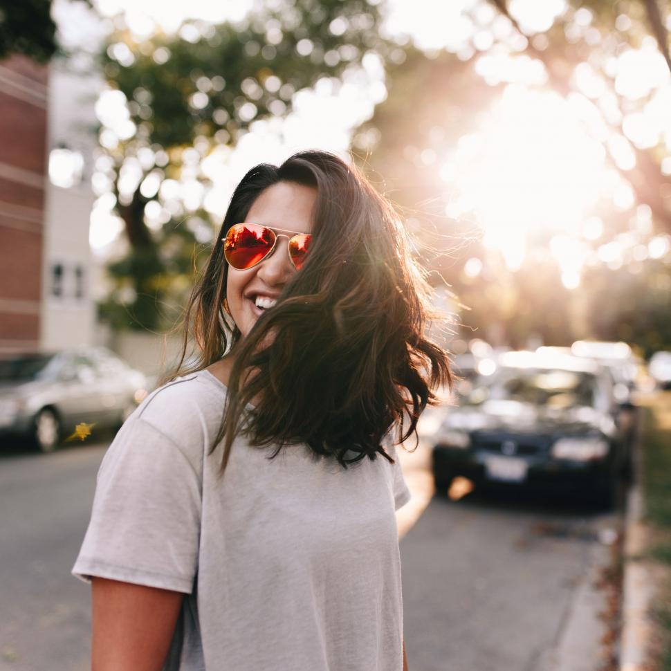 Free Image of Woman Walking Down Street With Windy Hair 
