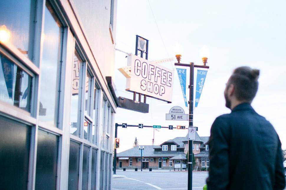 Free Image of Man Walking Past Coffee Shop on Street 