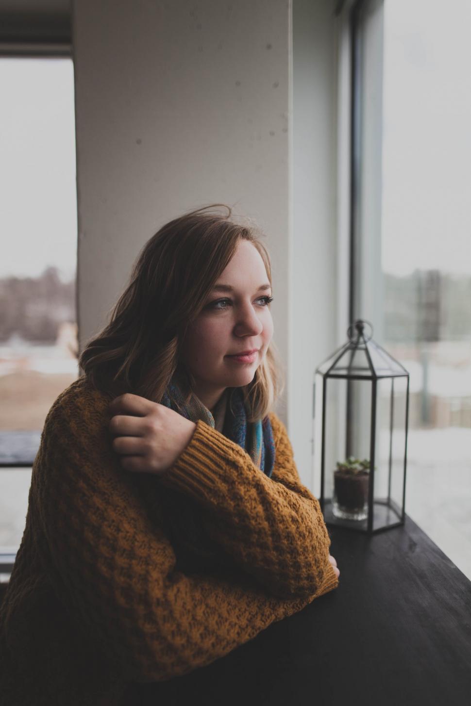 Free Image of Woman Sitting at Table Looking Out Window 