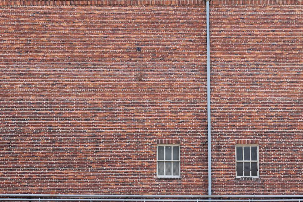 Free Image of Red Brick Building With Two Windows and a Street Sign 
