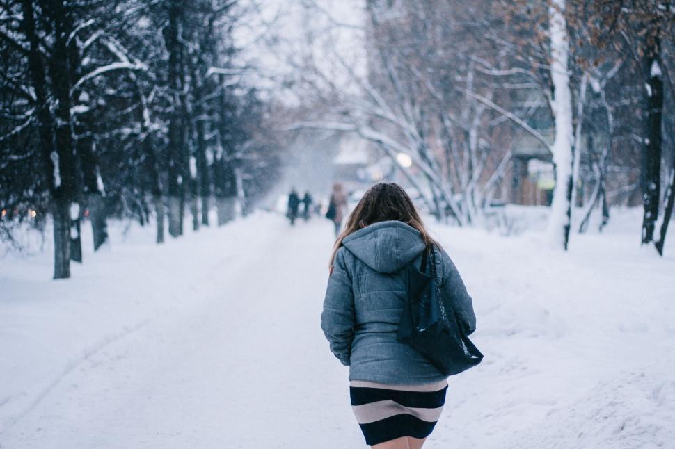 Free Image of Woman Walking Down a Snow Covered Road 