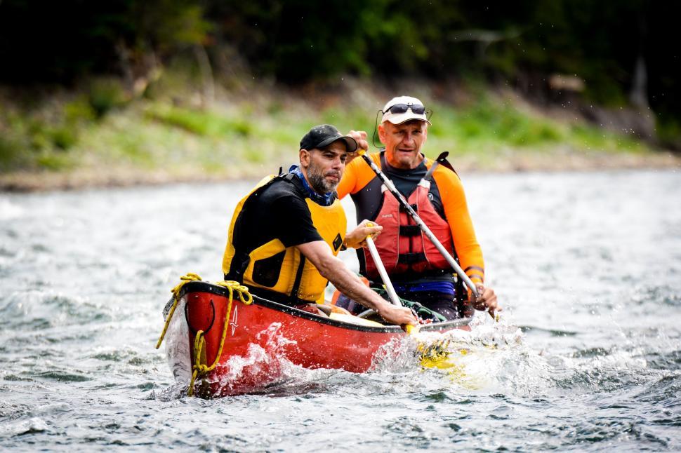 Free Image of Men Riding on the Back of a Red Boat 