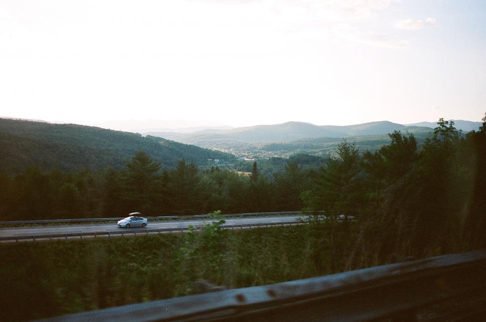 Free Image of Car Driving Down Road With Mountains in Background 