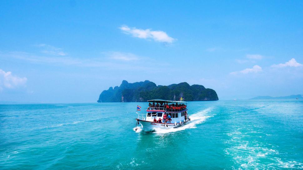 Free Image of Boat Traveling Through Ocean With Mountains in Background 