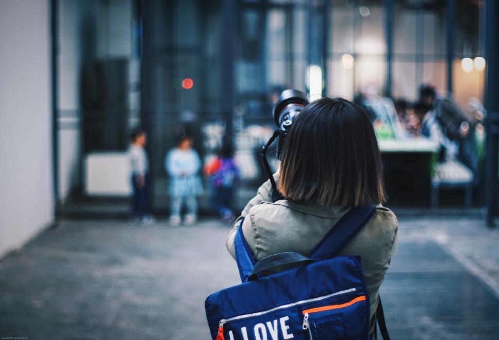 Free Image of Woman Taking Picture of People Walking Down the Street 