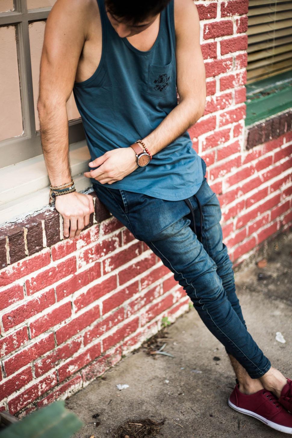 Free Image of Man Leaning Against Red Brick Wall 