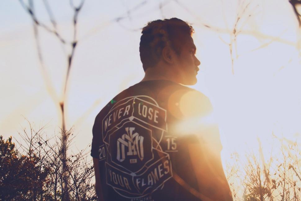 Free Image of Man Standing in Field With Sun Behind Him 