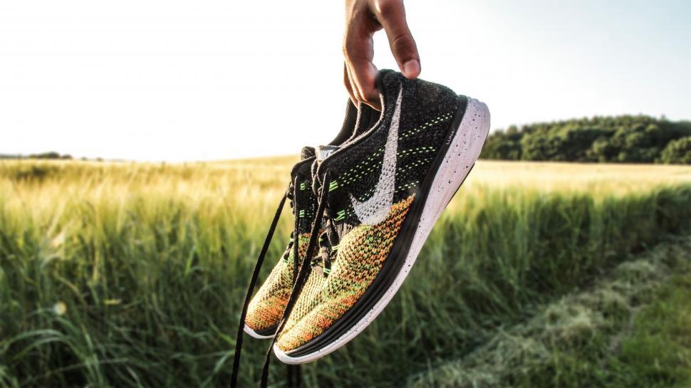 Free Image of Person Holding Pair of Sneakers in Field 
