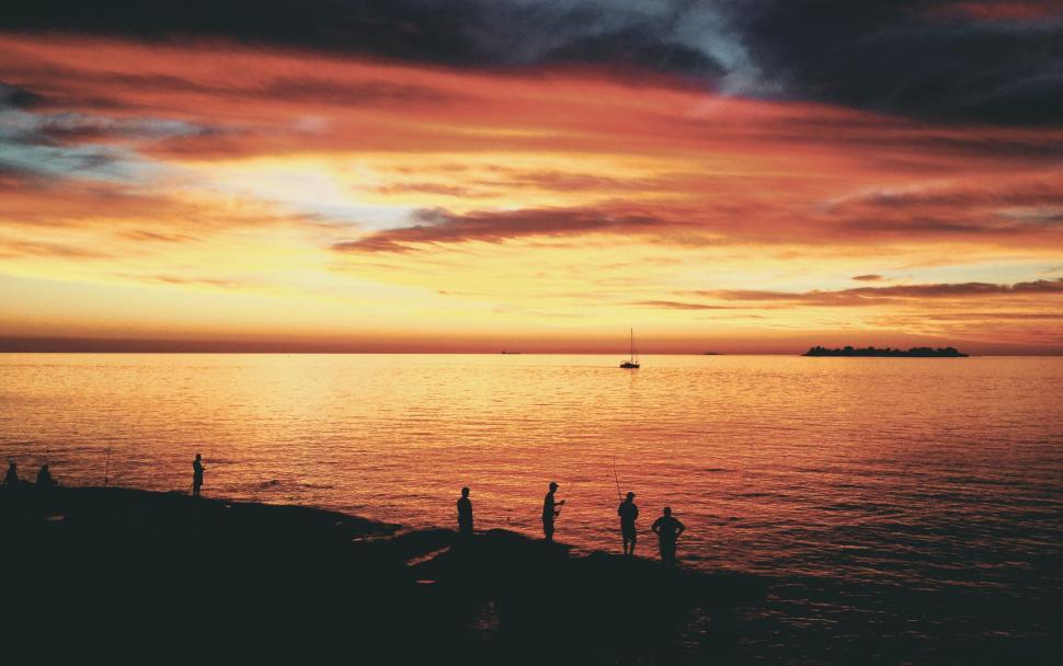 Free Image of Group of People Standing on Top of Beach Under Cloudy Sky 
