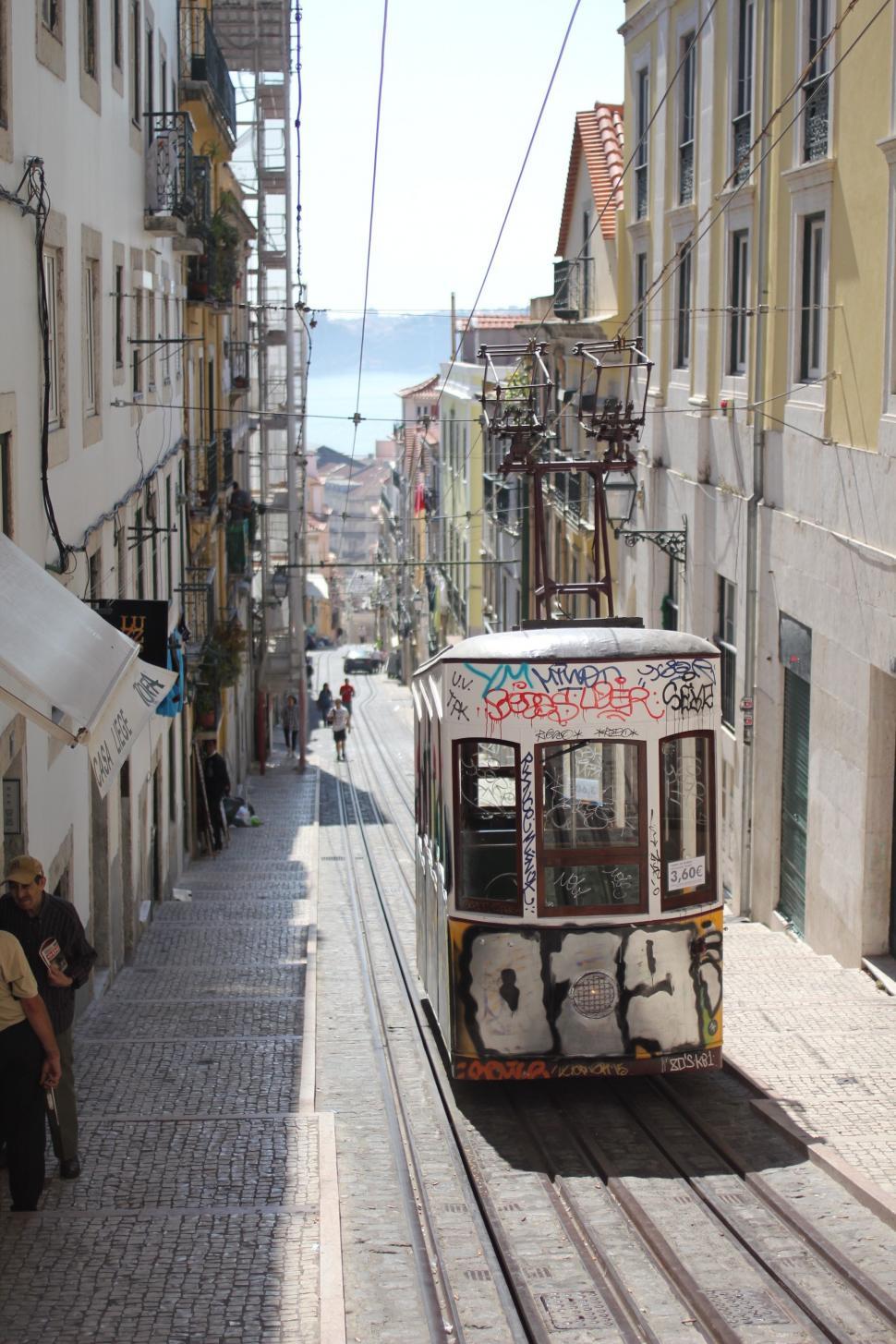 Free Image of Trolley Car Traveling Down Street Next to Tall Buildings 