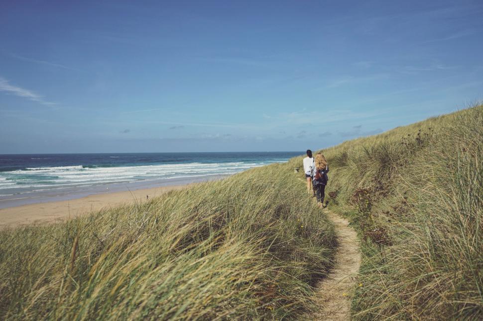 Free Image of Man Walking Down Path Next to Ocean 