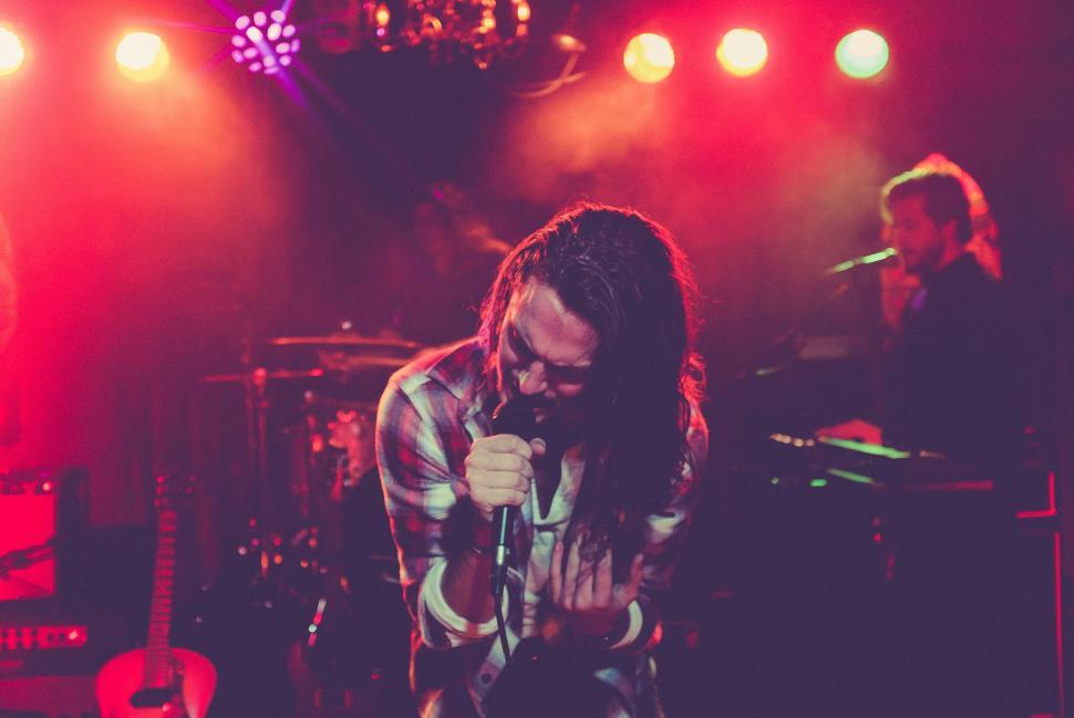Free Image of Man Standing on Stage Holding Microphone 