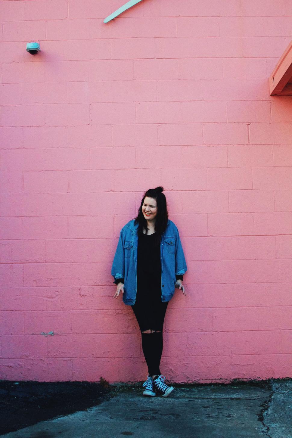 Free Image of Woman Standing in Front of Pink Wall 
