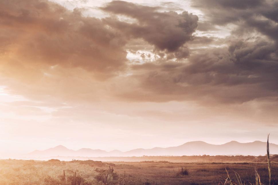 Free Image of Man Riding Horse Across Field Under Cloudy Sky 