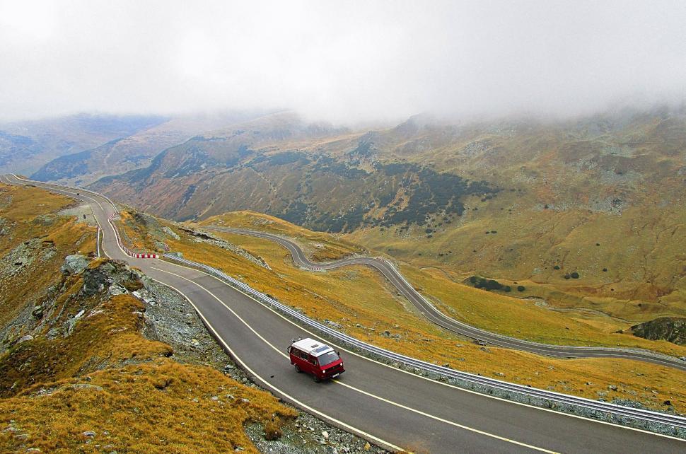 Free Image of Car Driving Down Mountain Road on Cloudy Day 