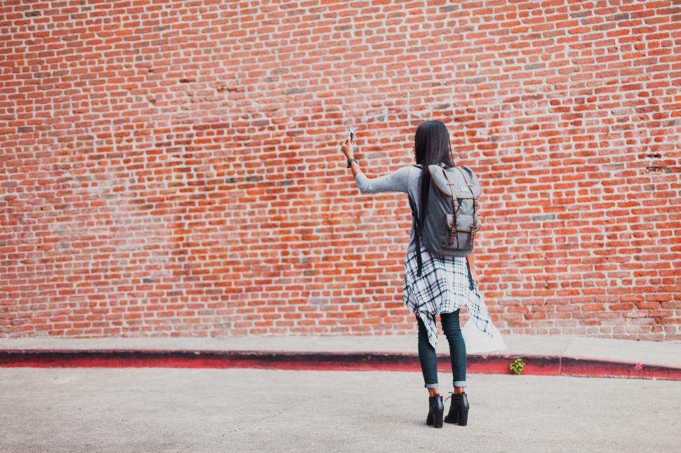 Free Image of Woman Standing in Front of Brick Wall 