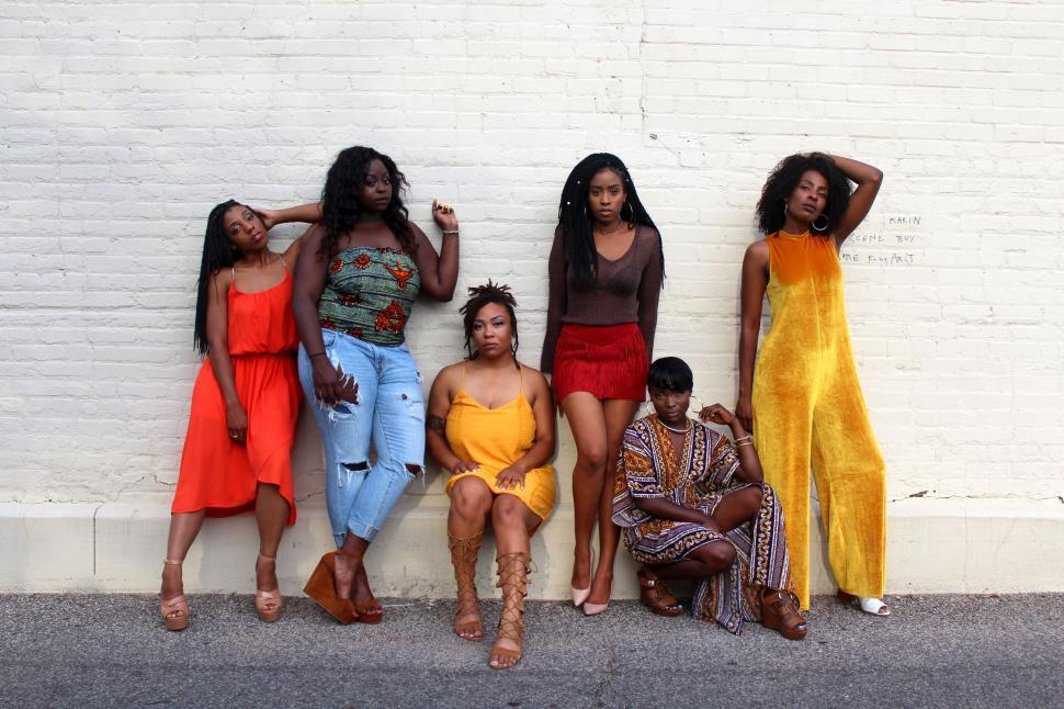 Free Image of Group of Women Standing Next to White Brick Wall 