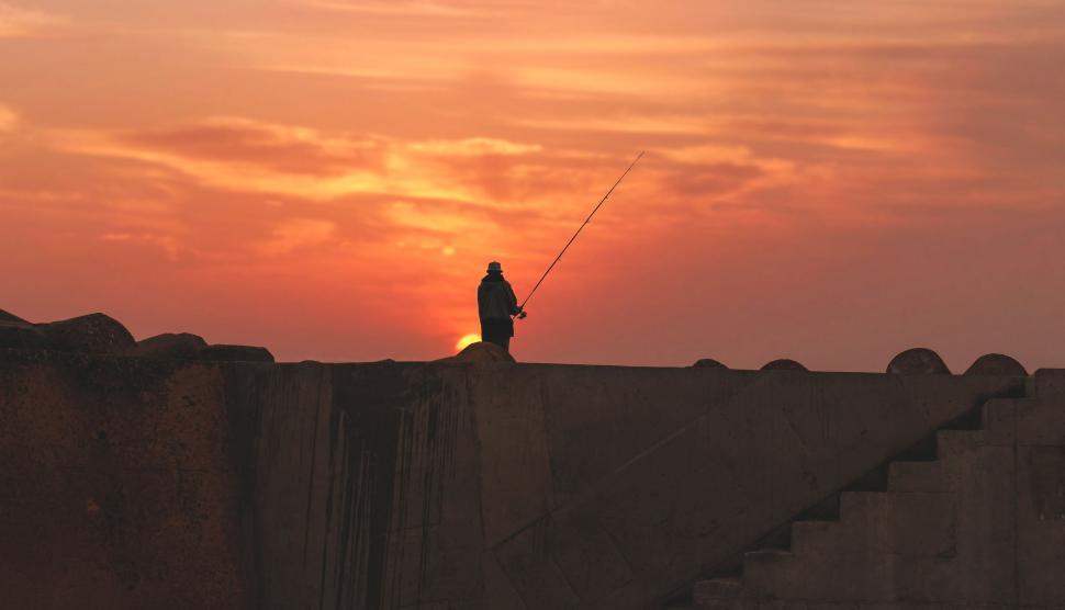 Free Image of Man Standing on Bridge With Fishing Pole 