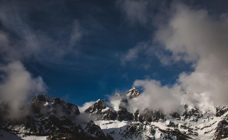 Free Image of Snow Covered Mountain Range Under Cloudy Sky 