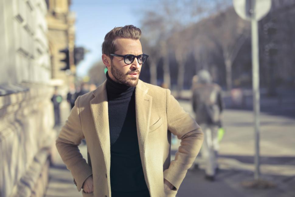 Free Image of Young Adult Man in long overcoat and sunglasses posing on the st 