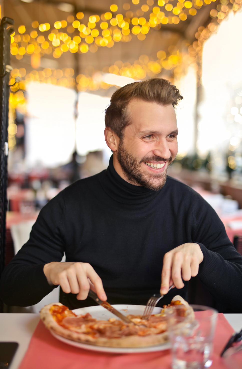 Free Image of Happy young man eating a pizza in restaurant 