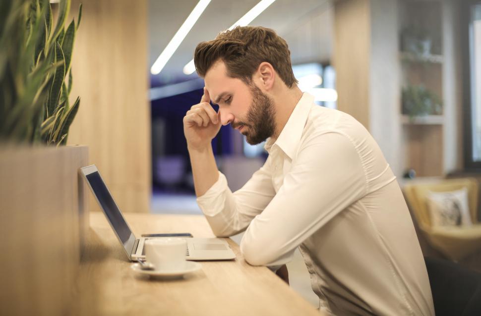 Free Image of Young Adult Man Looking at Laptop With His Hand on Temple 