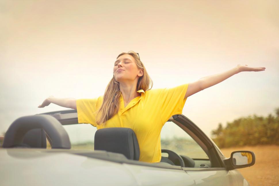 Free Image of Young Woman In Yellow Shirt Enjoying Weather With Open Arms 