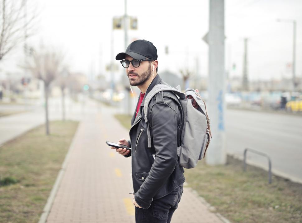 Free Image of Young Adult man wearing black leather jacket holding smartphone 