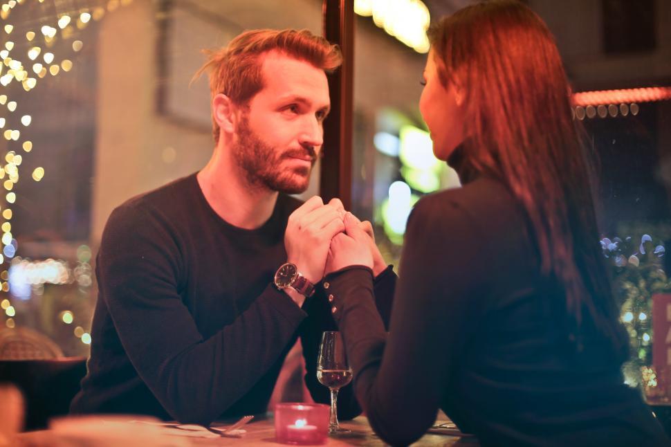 Free Image of Romantic couple holding hands together during a romantic dinner 