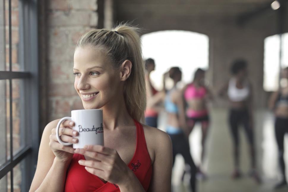 Free Image of Young Woman Wearing Red Tank Top Holding White Ceramic Mug 
