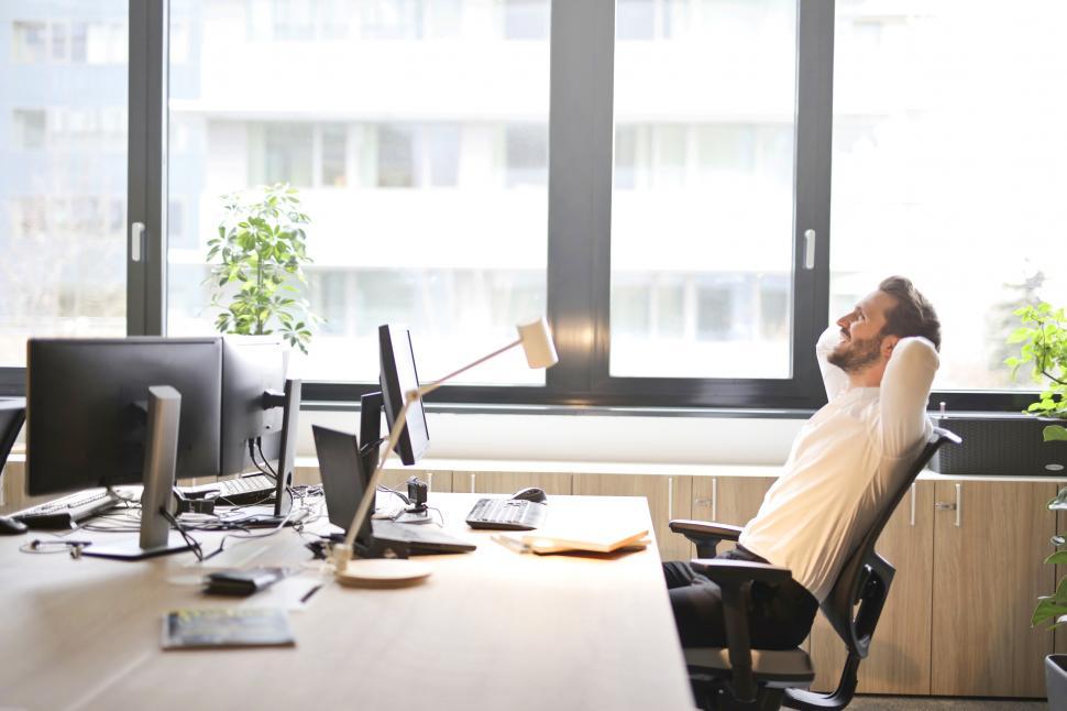 Free Image of Young Adult Man In White Shirt Laughing While Sitting on Office 
