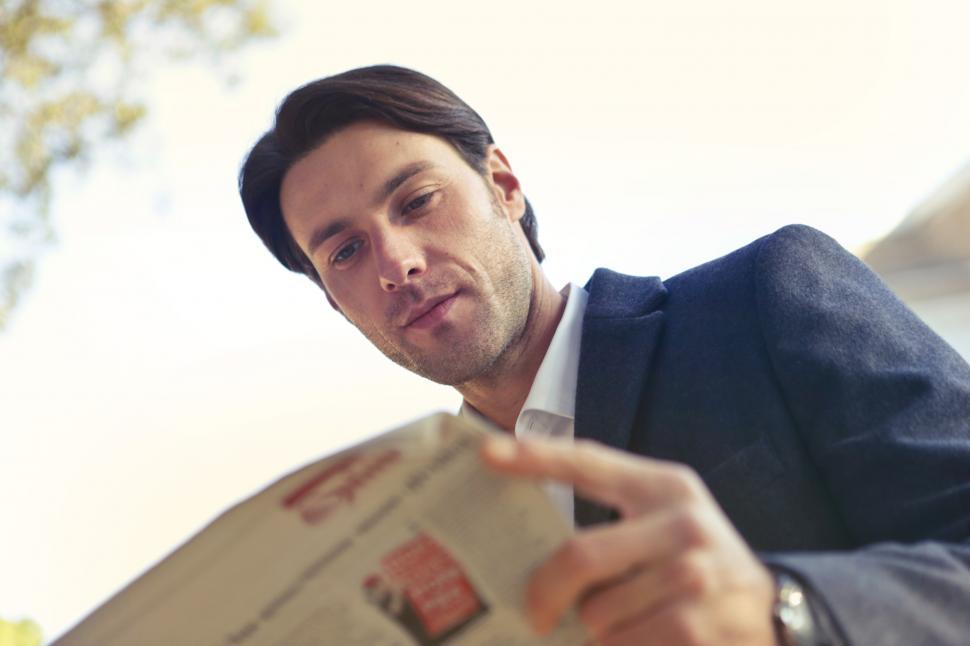 Free Image of Young Man In Blue Blazer Reading a Newspaper 