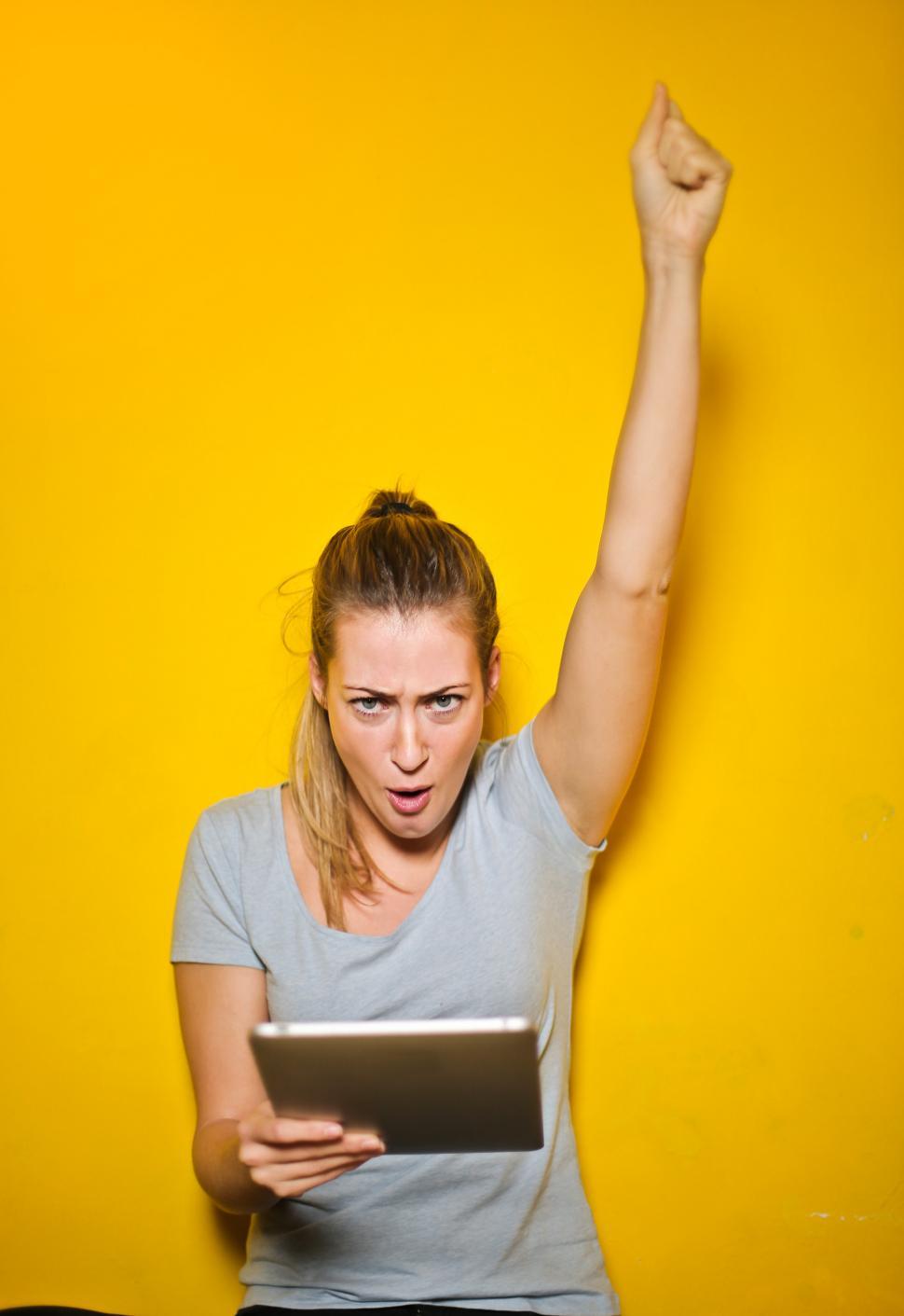 Free Image of Excited Young Woman Holding An iPad 